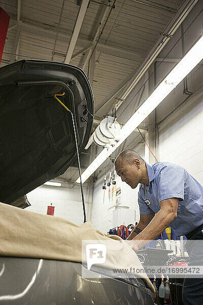 Ein Mechaniker aus einem pazifischen Inselstaat arbeitet in einer Autowerkstatt am Motorraum