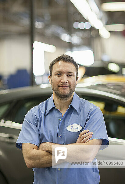 Automechaniker in einer Reparaturwerkstatt  junger weißer Mann in Uniform mit Namensschild