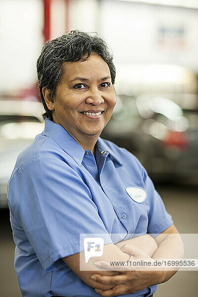Porträt einer hispanischen Mechanikerin in einer Autowerkstatt