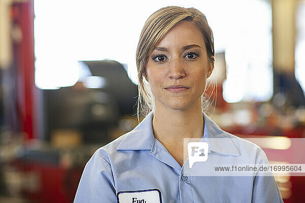 Porträt einer jungen kaukasischen Mechanikerin in einer Autowerkstatt
