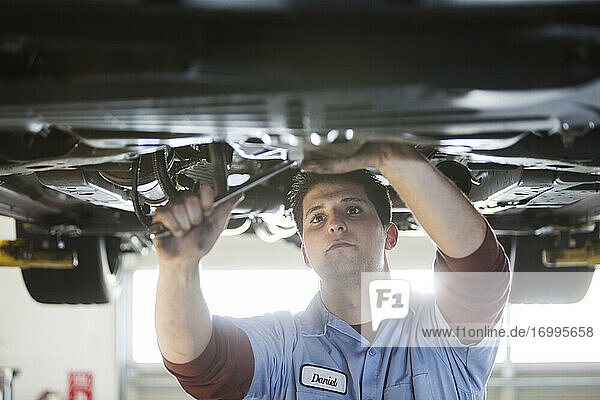 Mechaniker in einer Werkstatt arbeitet an der Unterseite eines Autos auf einer Hebebühne