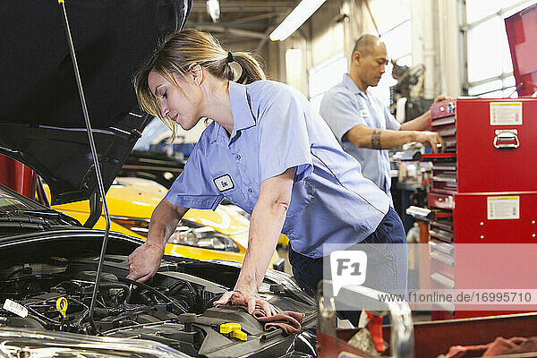 Kaukasische Mechanikerin arbeitet an einem Motor in einer Autowerkstatt