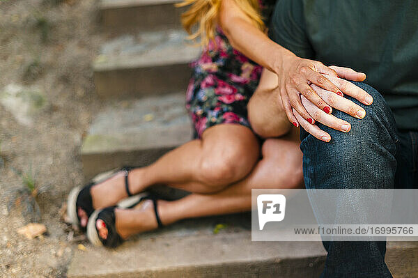 Romantisches Paar mit verschränkten Händen auf einer Treppe sitzend