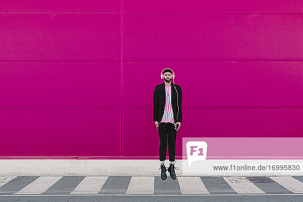 Businessman walking along a pink wall