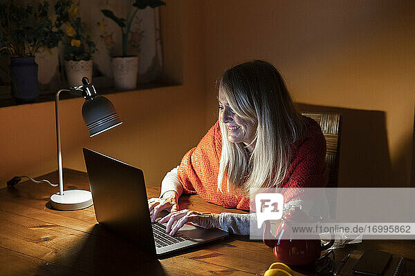 Frau benutzt Laptop  während sie zu Hause sitzt