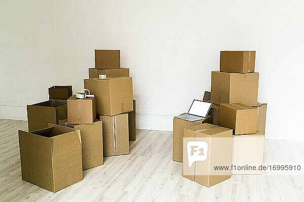 Stapel von Kartons mit Laptop im leeren Wohnzimmer