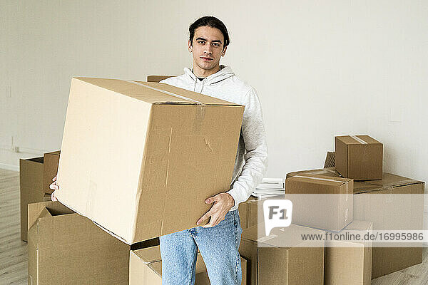 Junger Mann trägt Karton im neuen Haus