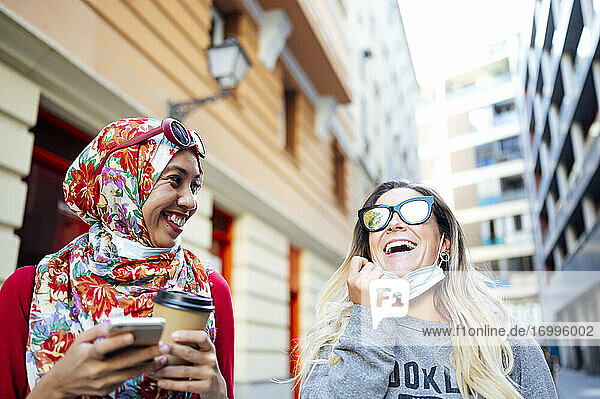 Fröhliche Freundinnen  die während der COVID-19 ihre Freizeit gemeinsam in der Stadt verbringen