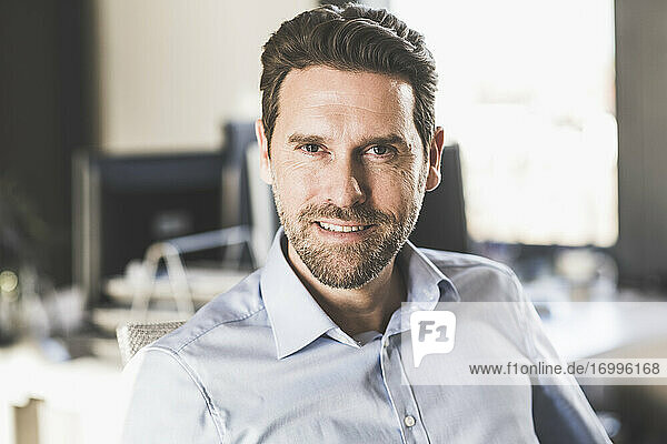 Mature businessman smiling while sitting at office