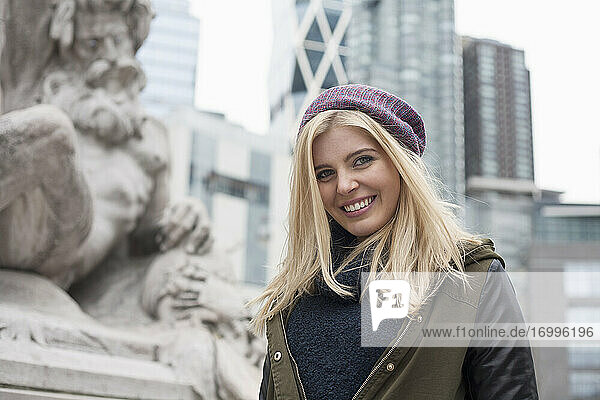Blonde Frau lächelt  während sie in der Stadt steht