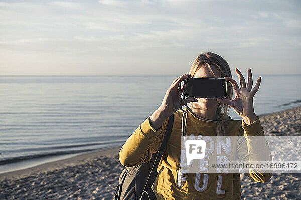Tourist beim Fotografieren mit dem Handy am Strand von Mecklenburg  Fischland-Darß-Zingst  Deutschland
