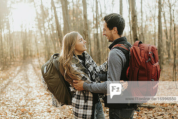 Young couple embracing in forest during autumn hike