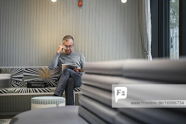 Geschäftsmann  der in einem modernen Café sitzt und an einem digitalen Tablet arbeitet