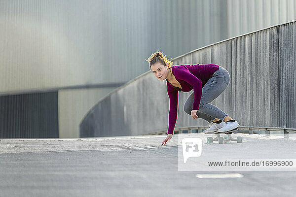Junge Frau  die auf einer Fußgängerbrücke Skateboard fährt