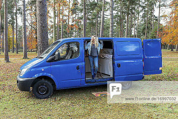 Mid adult woman leaning out on door of van at Cannock Chase