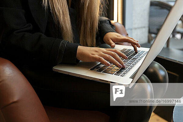 Young woman typing on laptop while sitting at cafe