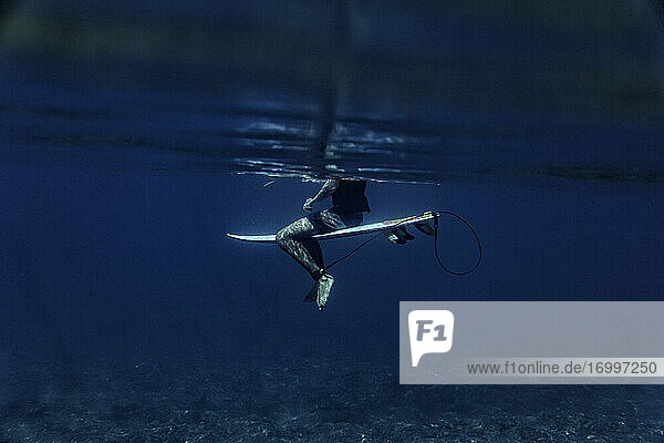 Surfer sitting on surfboard in blue sea at Maldives