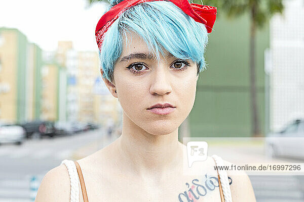 Porträt einer ernsten jungen Frau mit blau gefärbtem Haar