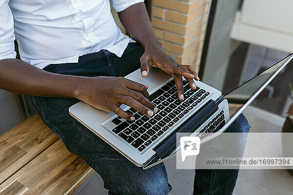 Geschäftsmann tippt auf einem Laptop  während er von zu Hause aus arbeitet