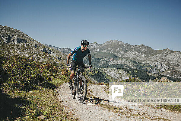 Männlicher Radfahrer fährt Mountainbike auf einem Weg gegen den Himmel  Nationalpark Picos de Europa  Asturien  Spanien