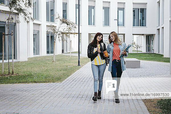 Young female students talking while walking around university campus