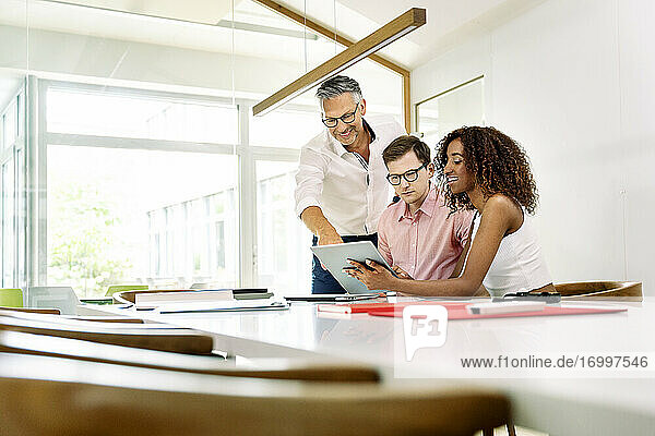 Business people working on digital tablet during meeting in boardroom