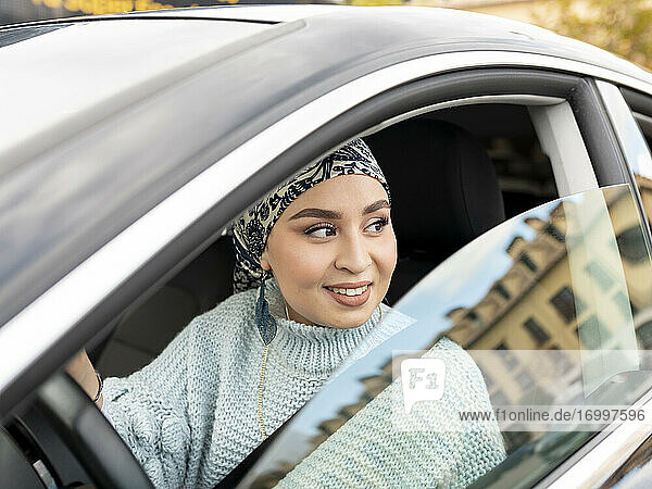 Woman looking away while sitting in car at city