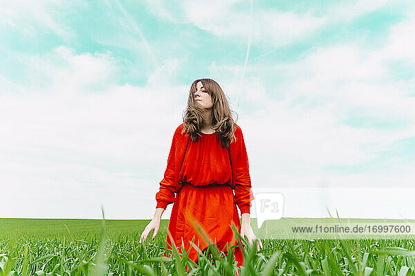 Frau in rotem Kleid entspannt sich auf einem Feld mit geschlossenen Augen