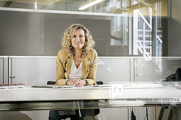 Mature businesswoman smiling at desk in office