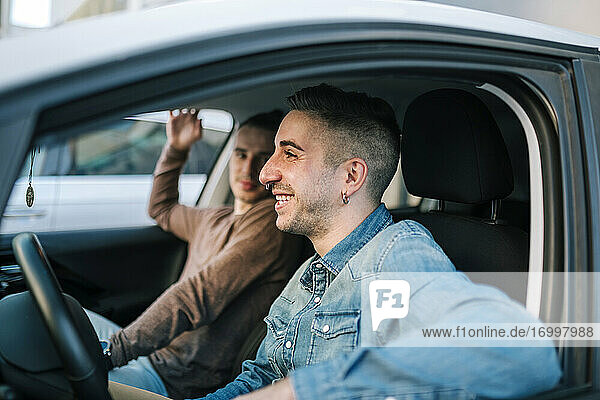 Smiling gay men sitting in car
