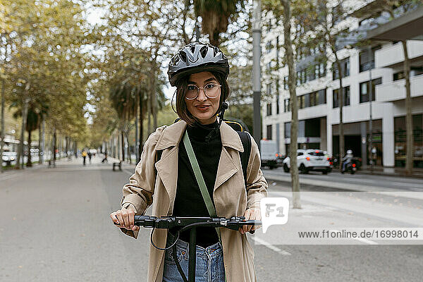 Mid erwachsene Frau stehend mit elektrischen Push-Roller auf der Straße in der Stadt