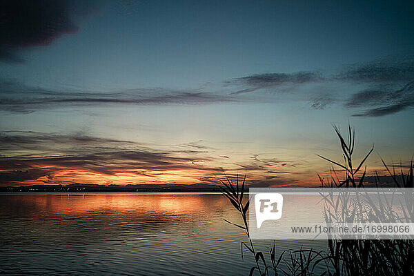 Malerischer Blick auf den See vor einem dramatischen Himmel bei Sonnenuntergang