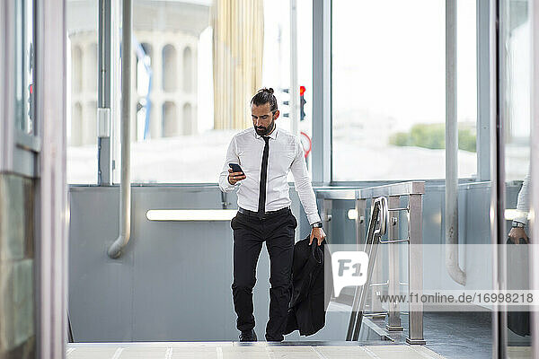 Businessman walking up stairs with smart phone in hand