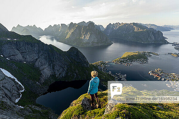 Wanderer bewundert die Aussicht  während er auf einem Berg bei Reinebringen  Lofoten  Norwegen steht