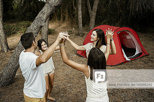 Happy family holding hands at campsite in forest during vacation