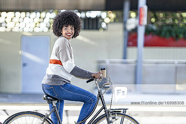 Happy woman looking away while sitting on bicycle at railroad station