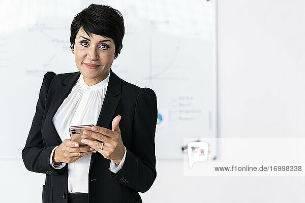 Porträt einer Geschäftsfrau  die mit einem Smartphone in der Hand posiert