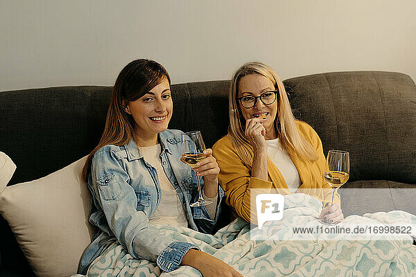 Mutter und Tochter genießen Wein  während sie im Wohnzimmer fernsehen