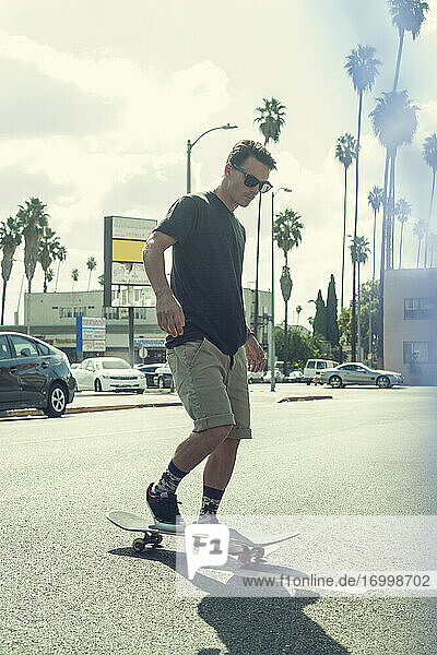 Junger Mann fährt Skateboard auf der Straße in der Stadt