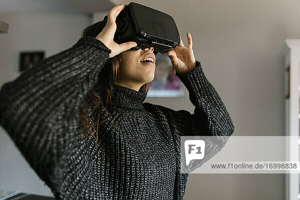 Teenager-Mädchen benutzt einen Virtual-Reality-Simulator  während sie zu Hause steht