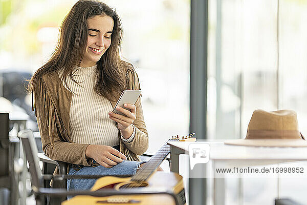Lächelnde Frau  die ihr Smartphone benutzt  während sie in einem Cafe sitzt