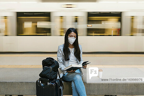 Frau liest ein Buch  während sie in der U-Bahn-Station gegen einen fahrenden Zug sitzt