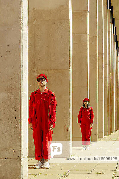 Junges Paar in roten Overalls und Hüten steht in einer Reihe