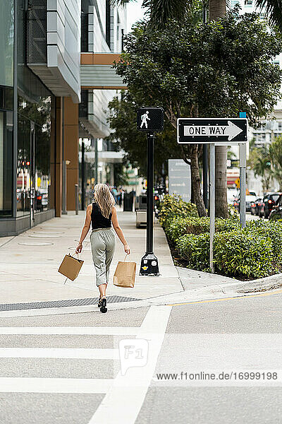 Woman with shopping bag walking on street in city