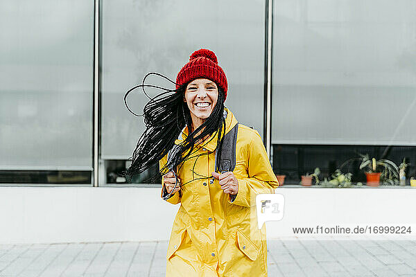 Frau in gelbem Regenmantel steht auf der Straße