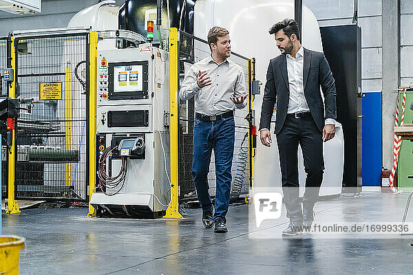 Businessman with manager discussing while walking in manufacturing factory
