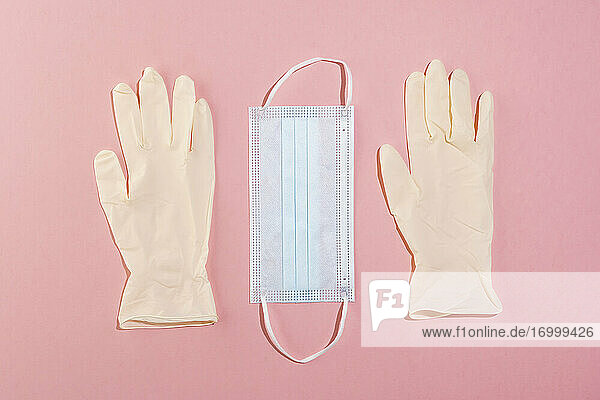 Studioaufnahme einer Gesichtsschutzmaske und eines Paars chirurgischer Handschuhe