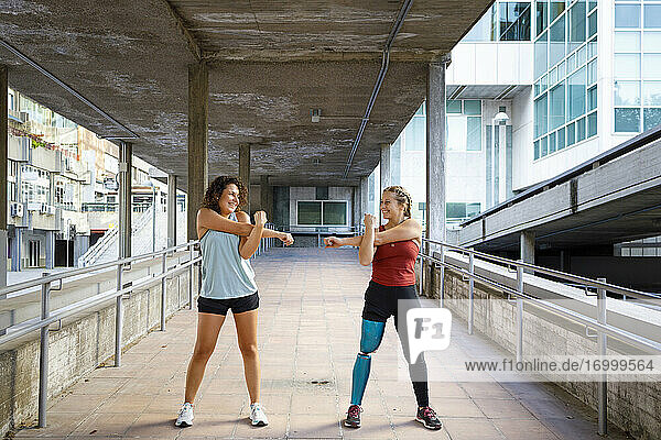 Sportlerin mit Beinprothese  die mit einem Freund auf einer Brücke stehend trainiert