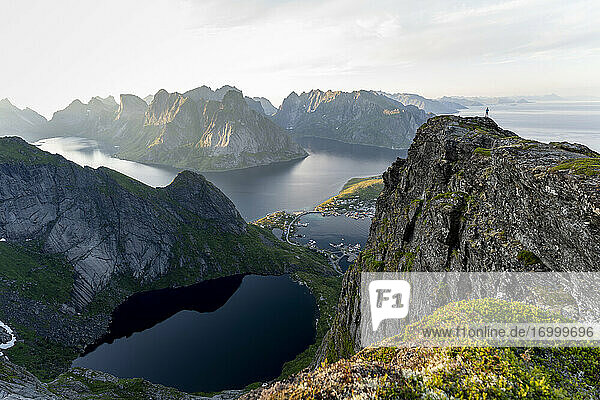 Frau steht auf einem Berg und bewundert die Aussicht bei Reinebringen  Lofoten  Norwegen