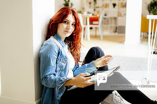 Junge Geschäftsfrau mit digitalem Tablet und Kreditkarte beim Einkaufen  während sie im Büro sitzt